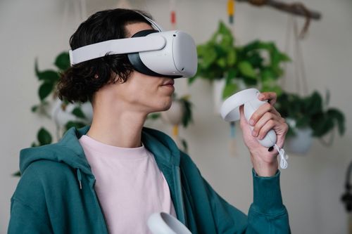 Free Young male gamer using controller and VR goggles for playing video game at free time at home Stock Photo