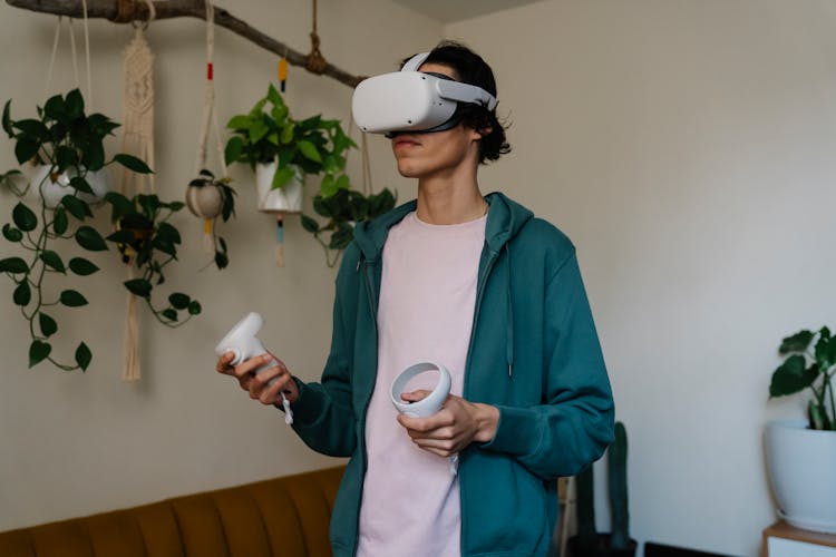 Gamer In VR Goggles Playing Video Game At Home