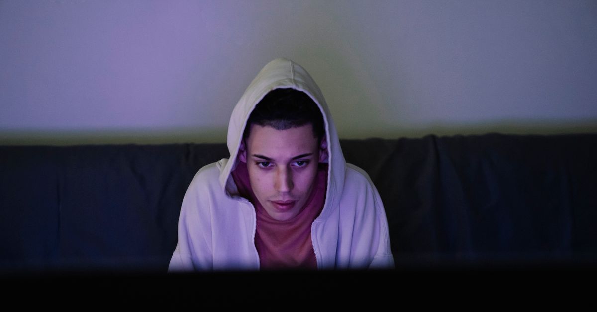 Person watching a glowing screen intently in a dim room