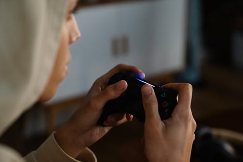 Crop ethnic man with gamepad playing video game at home