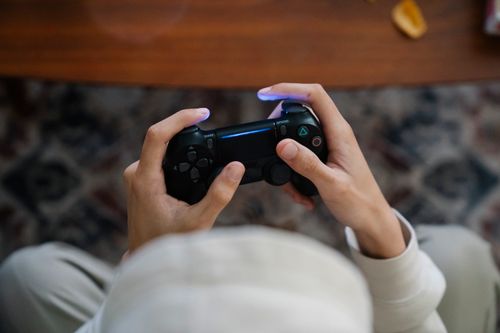 Free From above of crop unrecognizable male with console controller playing video game in living room Stock Photo