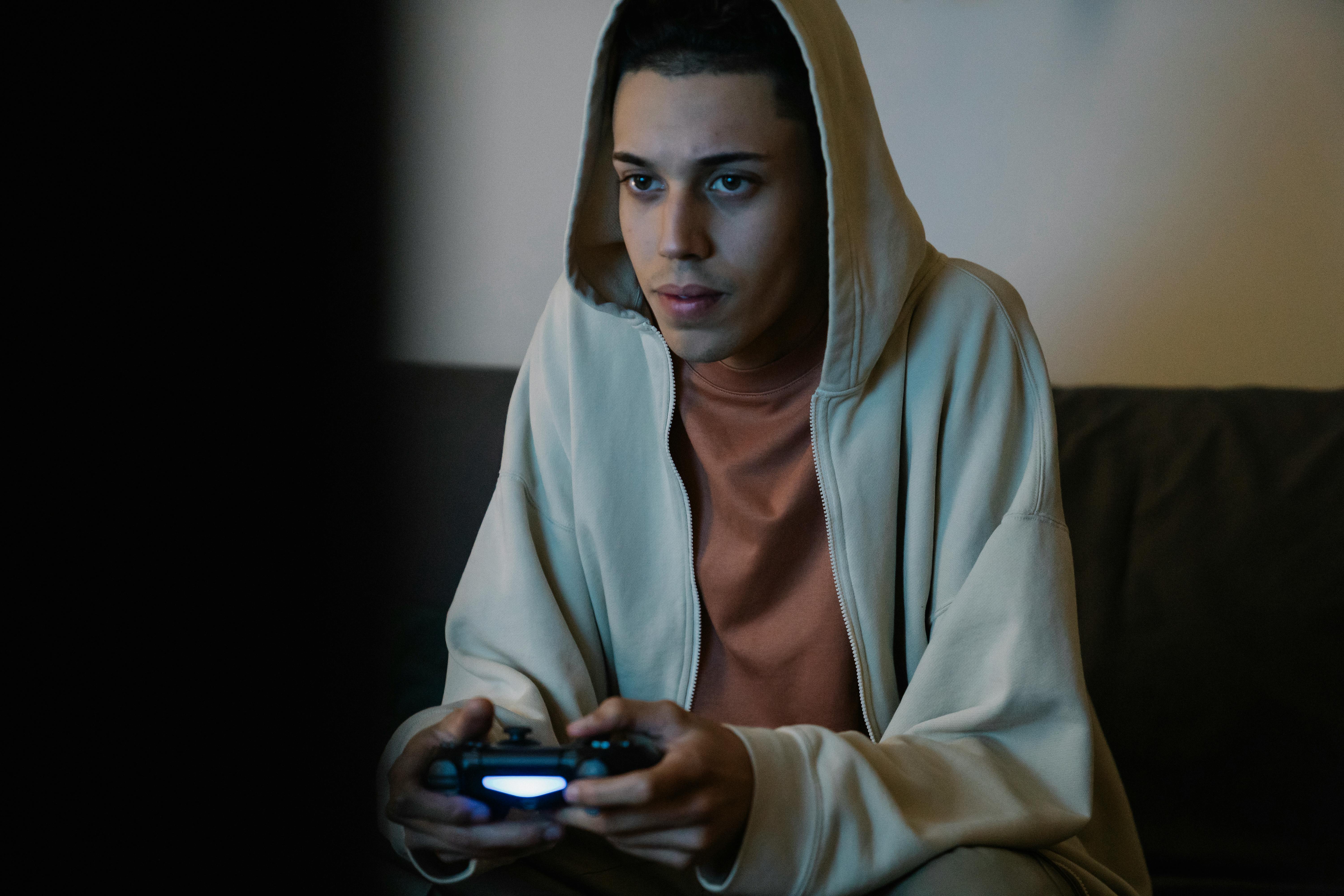 ethnic man with gamepad playing video game in room