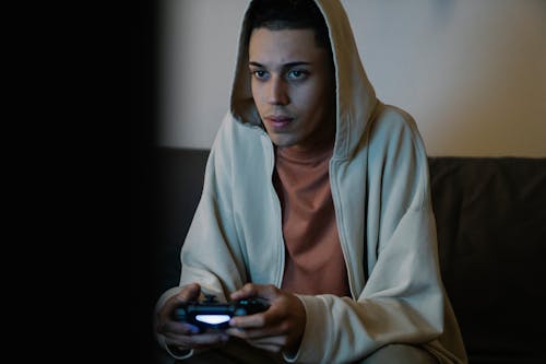 Ethnic man with gamepad playing video game in room