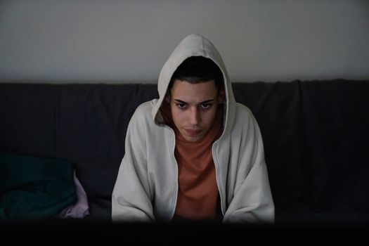 Focused ethnic man in hoodie on couch in house
