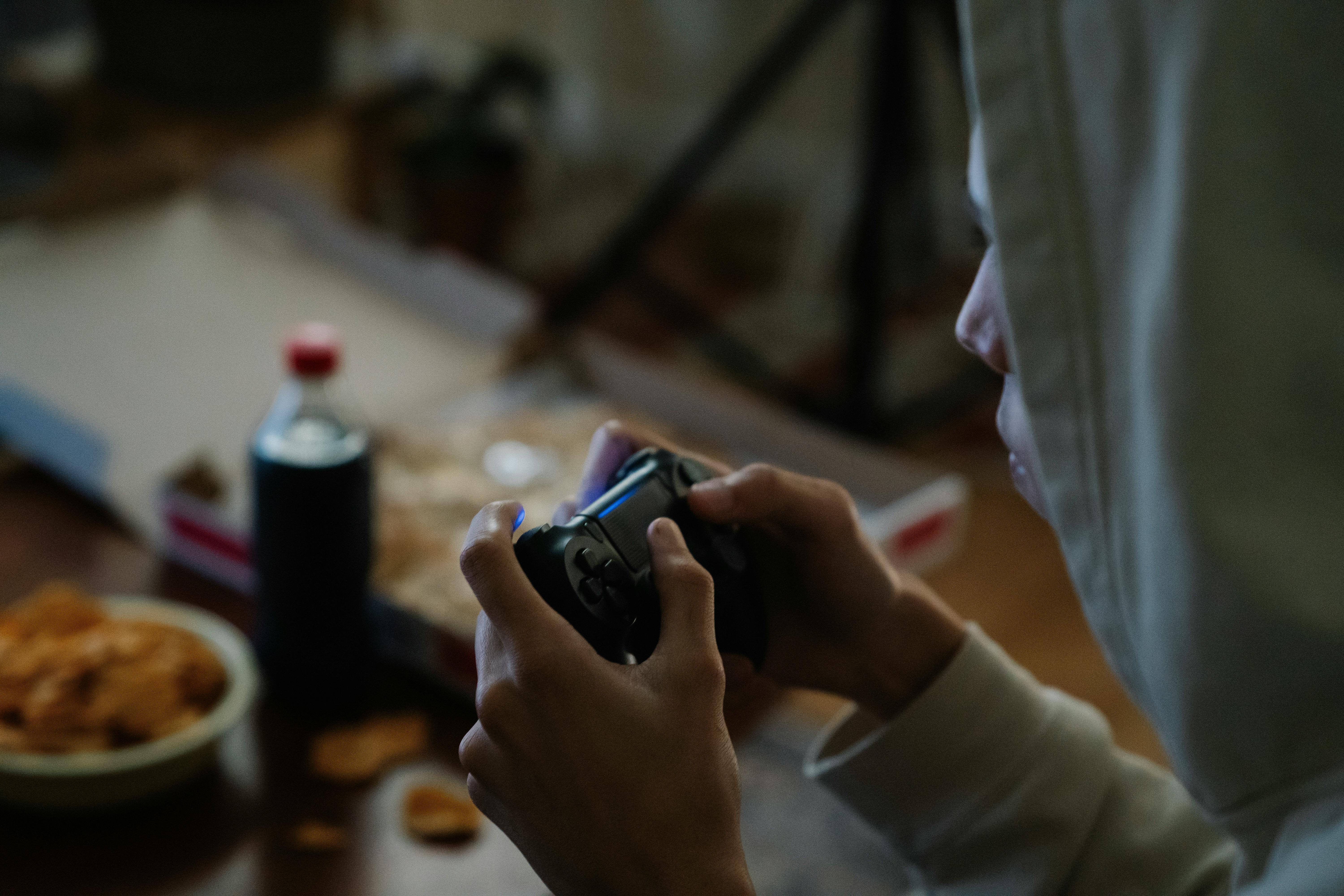 crop gamer with console controller playing video game in house