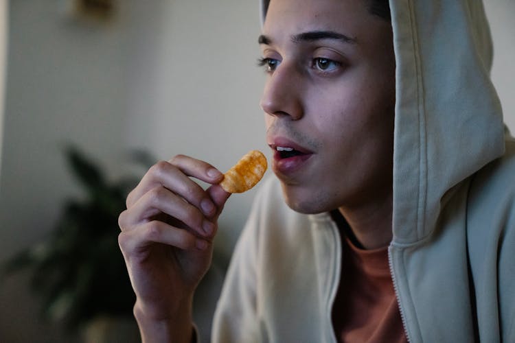 Crop Ethnic Man With Potato Chip At Home