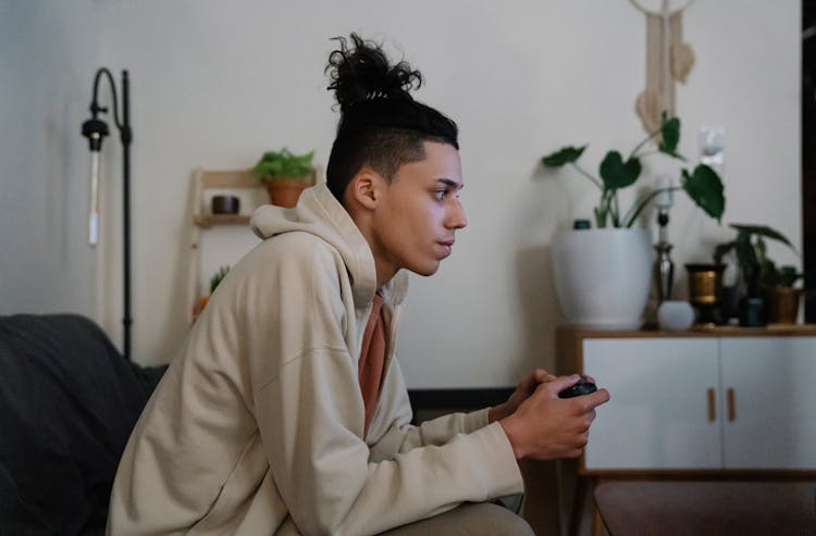 Ethnic Man With Gamepad Playing Video Game In Living Room