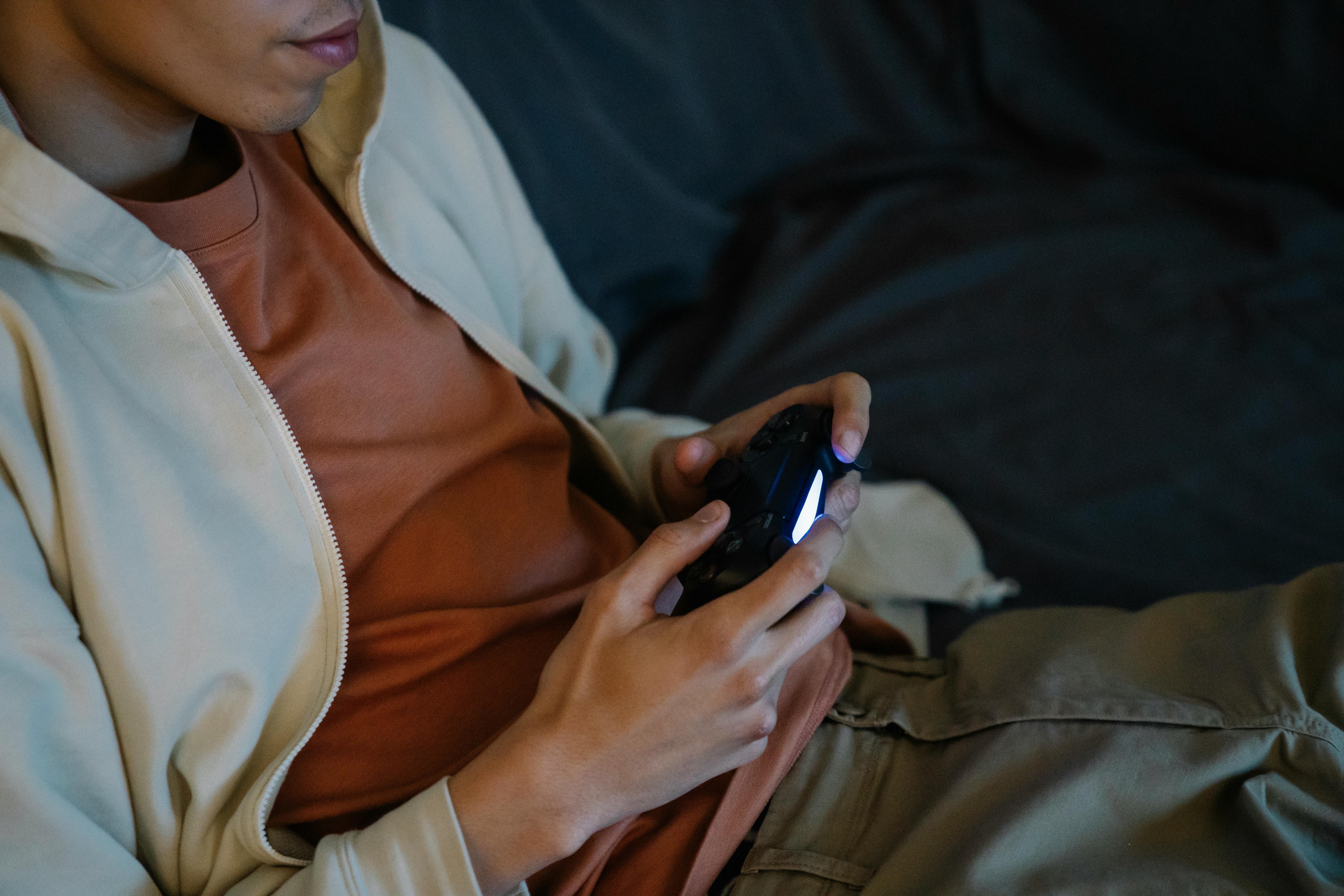 crop gamer with joystick playing video game on sofa