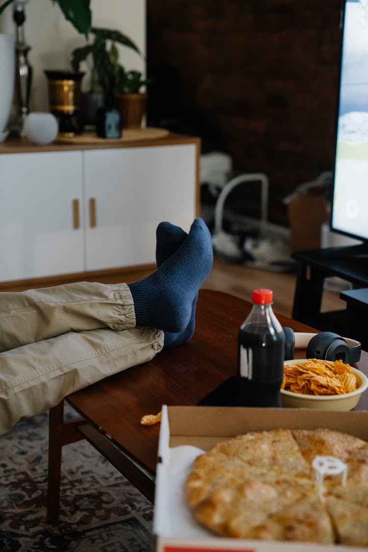 Faceless Person At Table With Takeaway Pizza And Cola