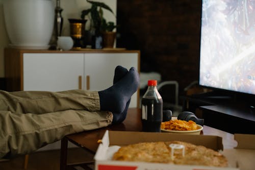 Crop person with crossed legs on table against monitor