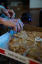 Crop anonymous person taking slice of delicious pizza from box in dimly lit