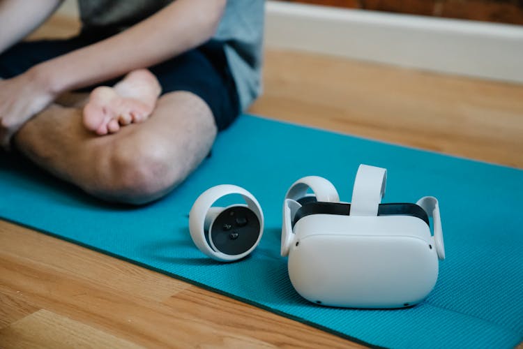 VR Glasses On Mat Near Person With Crossed Leg