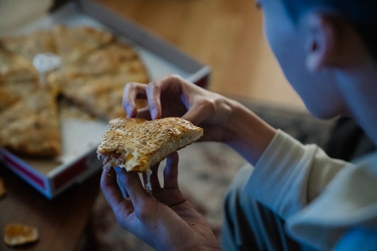 Crop Person Holding Bitten Piece Of Pizza