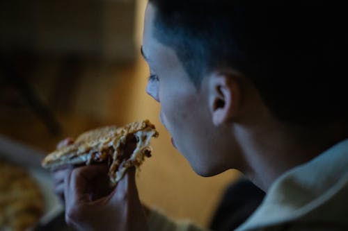 Hungry man eating piece of pizza