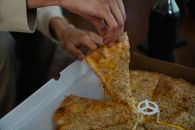 Crop unrecognizable person treating with slice of tasty pizza from carton box spending evening at home
