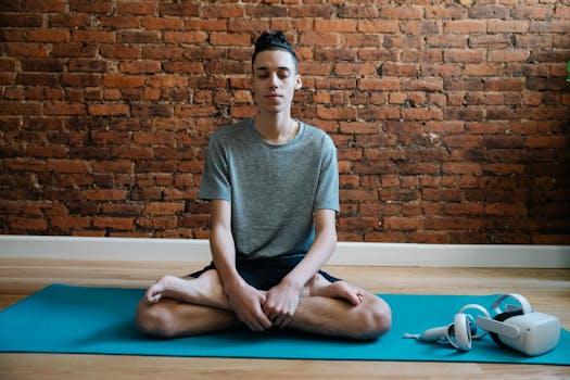 Full body of focused male teenager in activewear meditating in lotus pose on mat near VR glasses