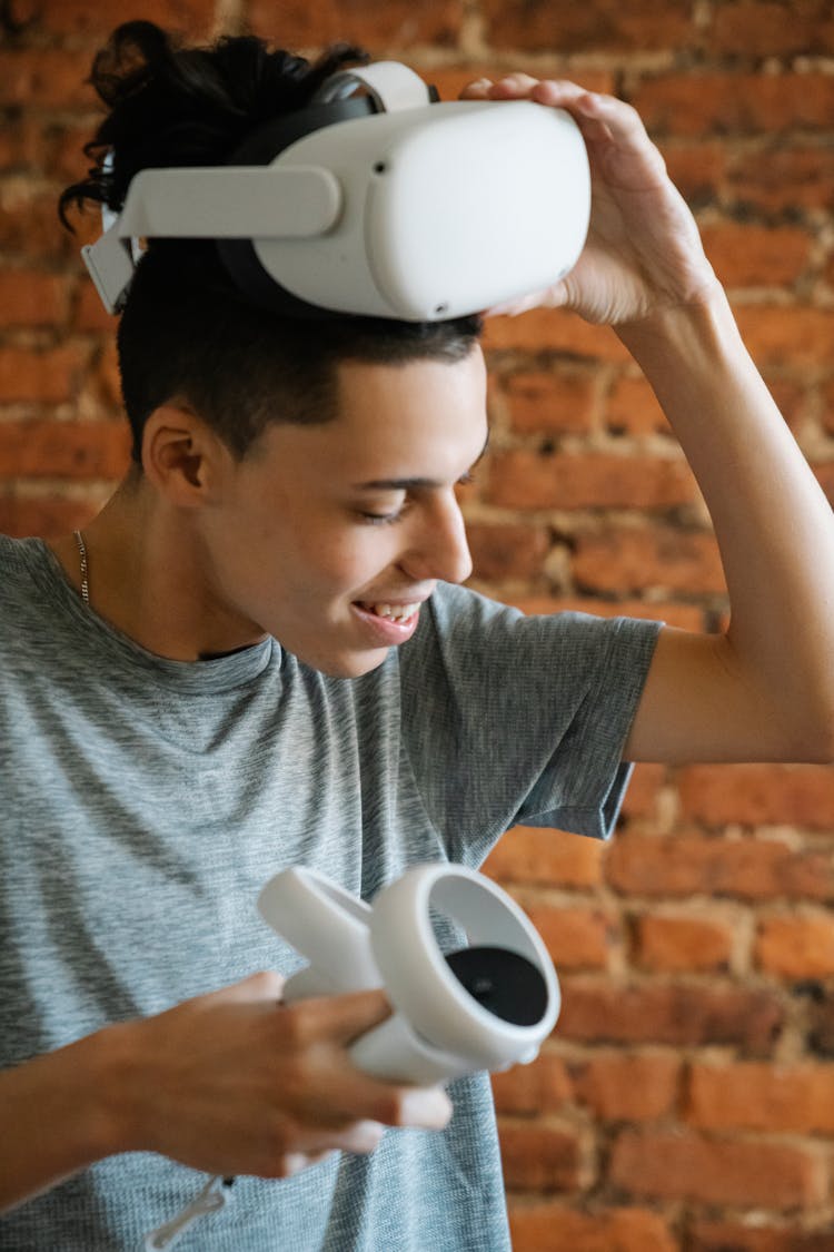 Teen With Controller Taking Off VR Glasses