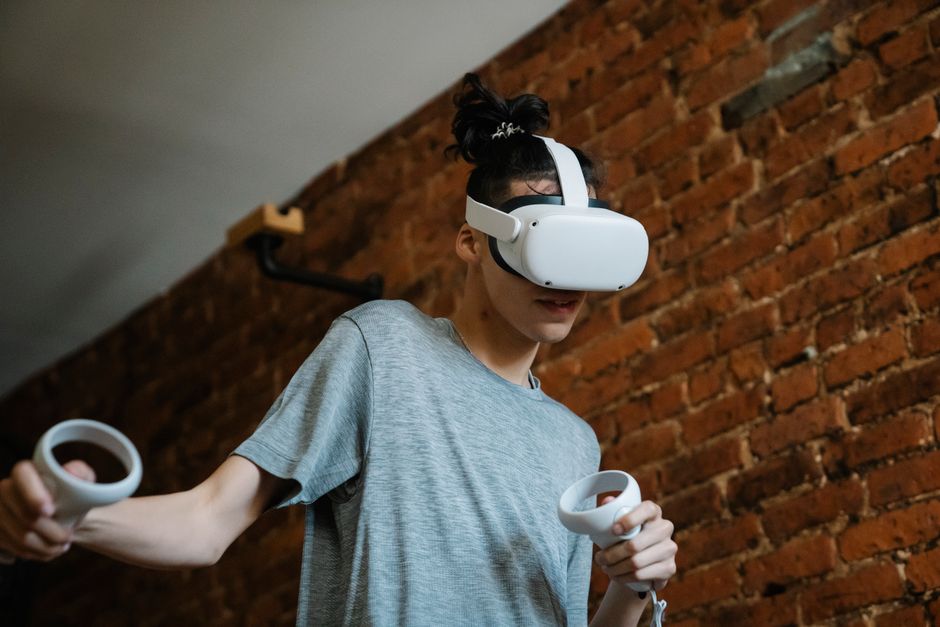 VRヘッドセットとコントローラーを使って室内でバーチャルリアリティゲーム体験を楽しむティーン。
