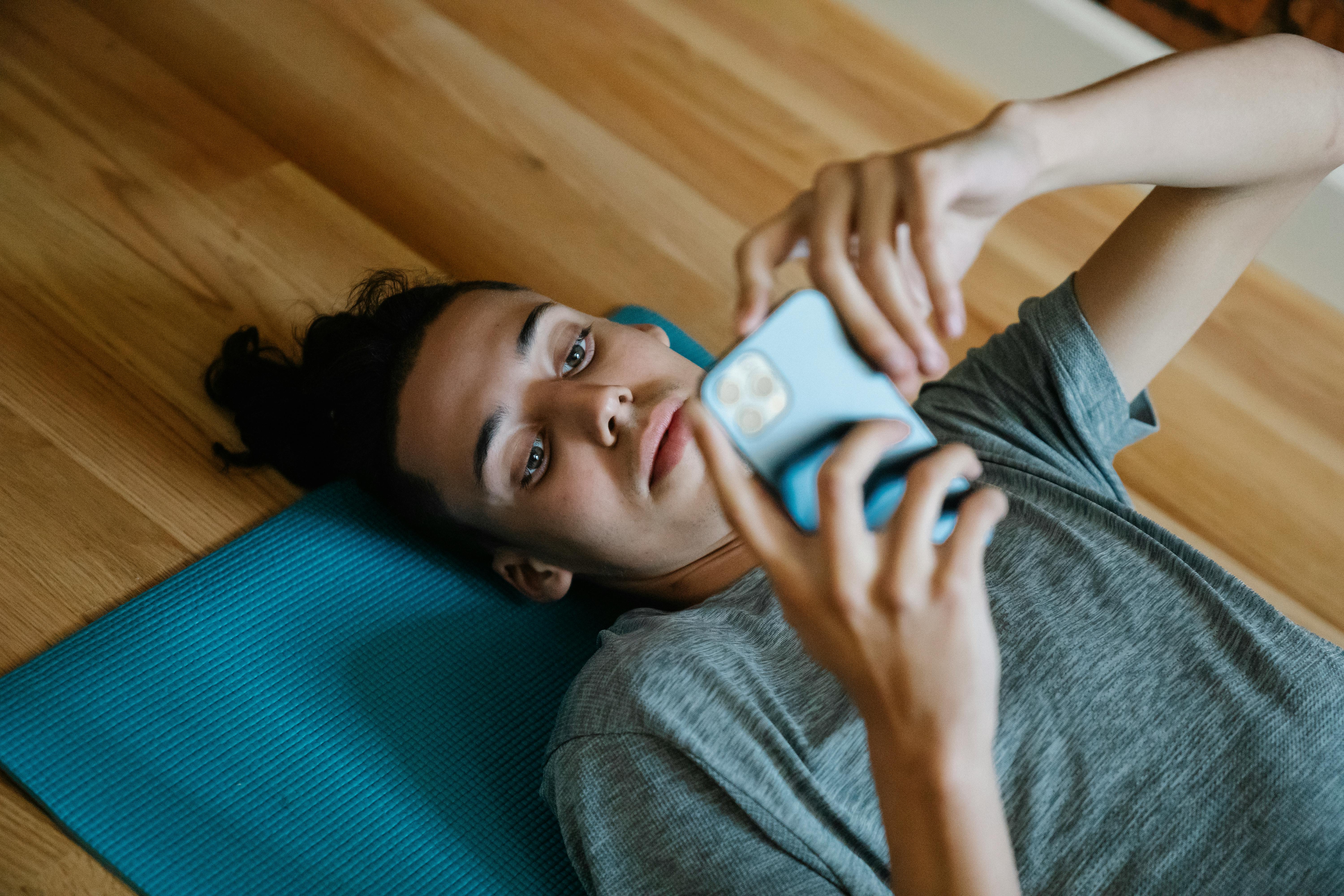 young man lying on floor and using smartphone