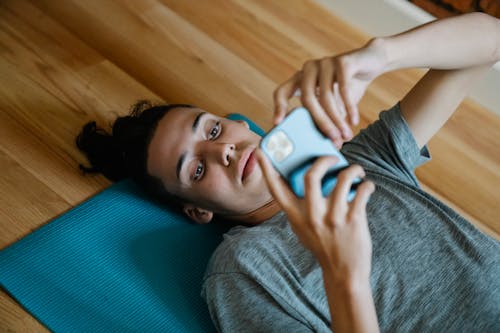 Young man lying on floor and using smartphone
