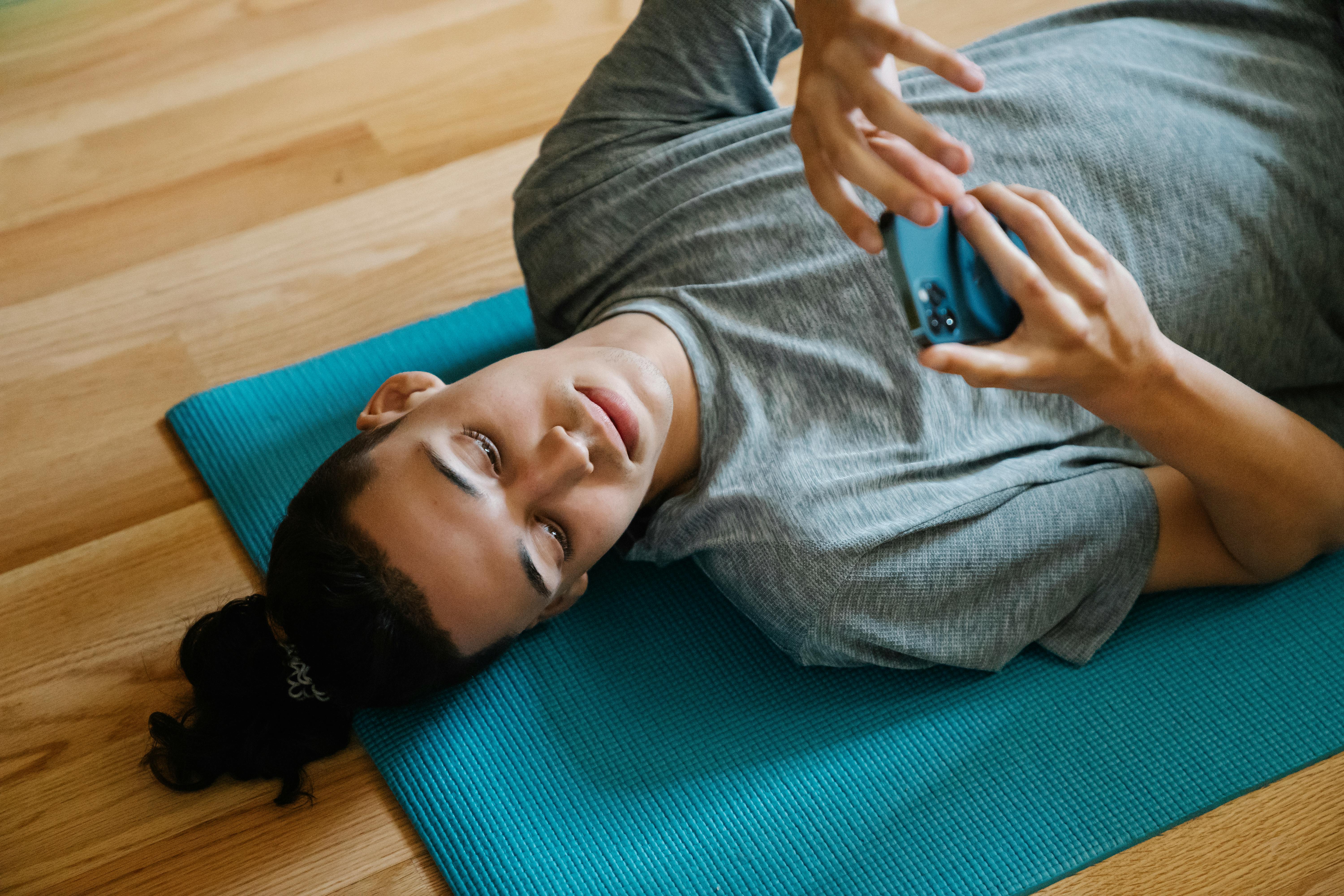 young man lying on mat with phone