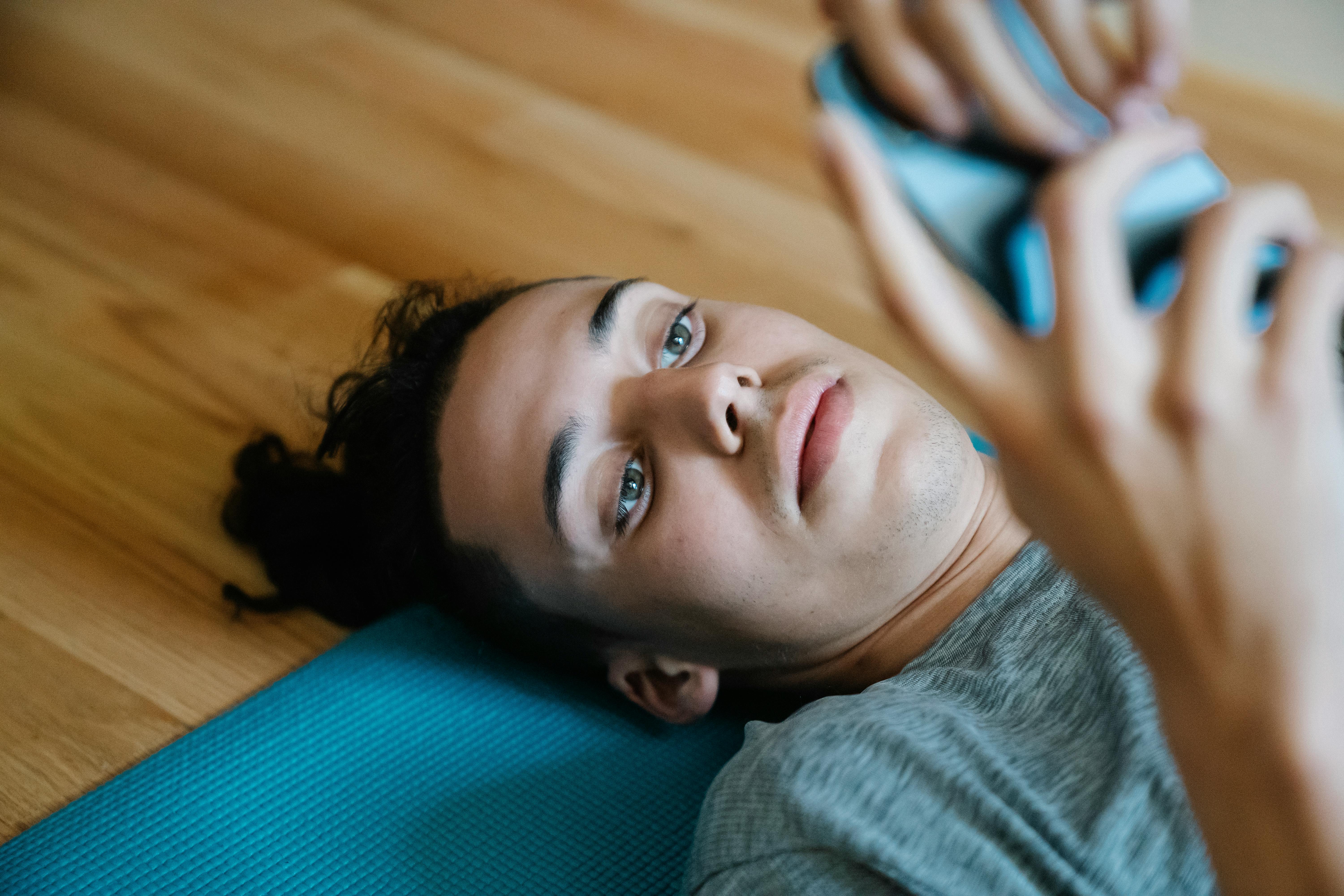 male lying on floor and messaging on smartphone