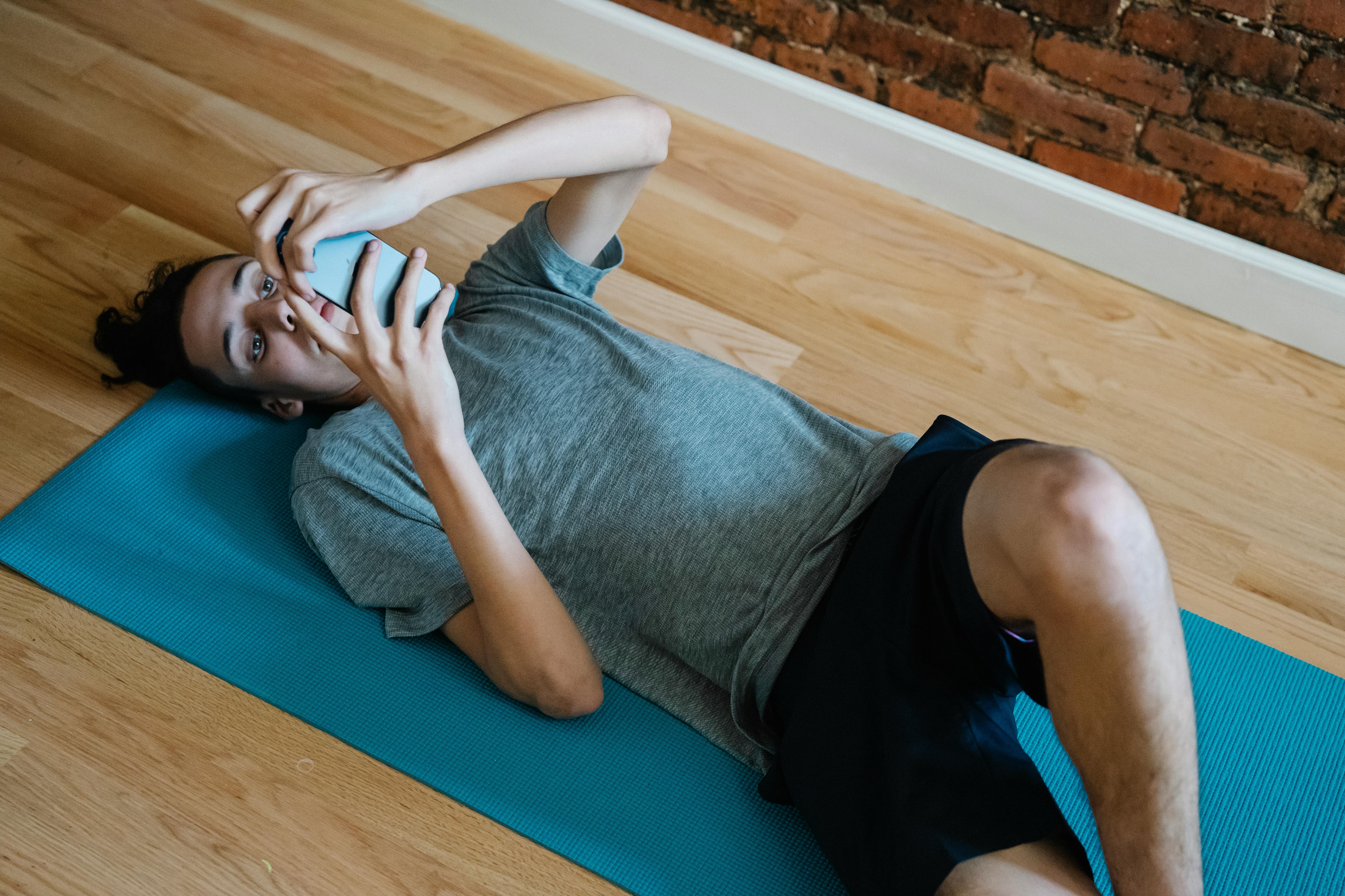 young man resting on mat with cellphone