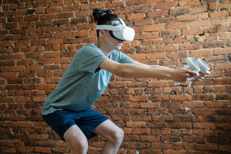 Man In Goggles Of Virtual Reality With Controllers