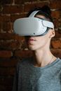 Unrecognizable young man experiencing goggles of virtual reality while standing in room with brick walls