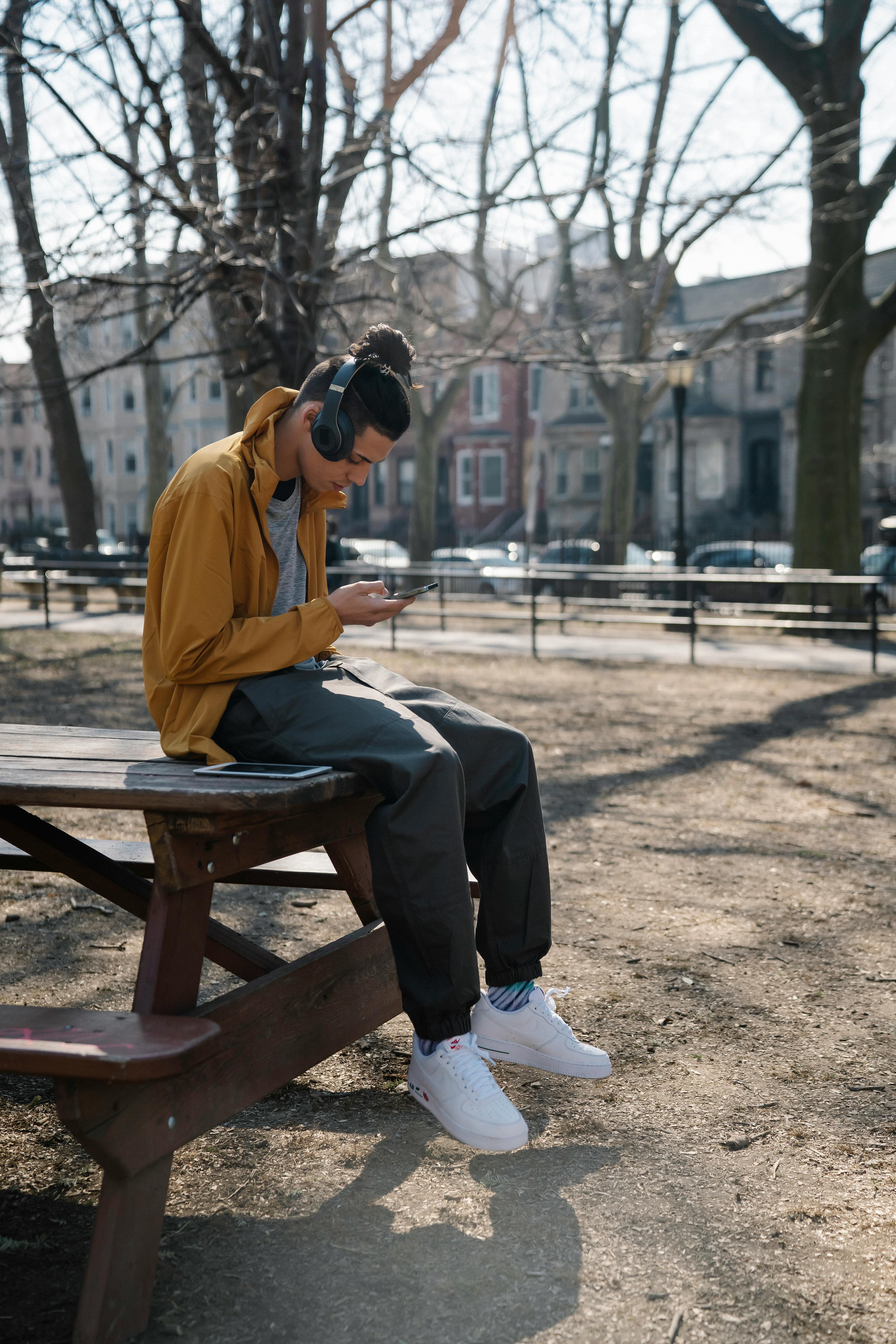 concentrated boy with earphones browsing smartphone in park