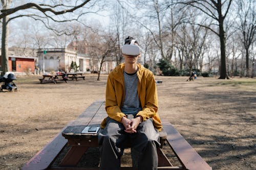 Free Young man sitting on bench in park with VR headset Stock Photo