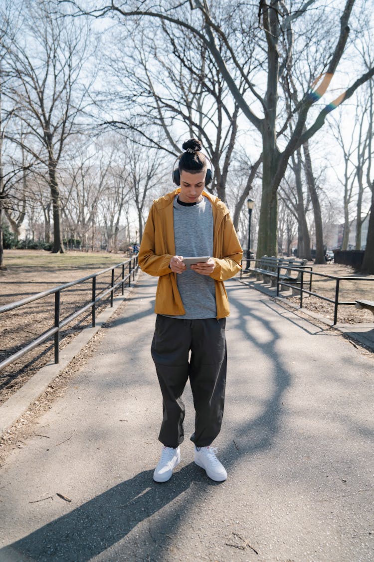 Male Teenager Standing On Footpath And Listening To Music