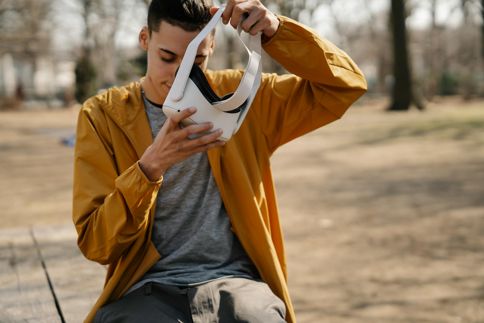 Young man sitting in a park exploring virtual reality with a headset.
