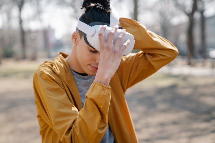 Male Teenager Putting On VR Headset In Nature