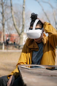 A person using VR headset outdoors during a sunny day, seated at a park bench.