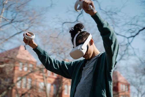 Free From below of anonymous male playing game with VR goggles on blurred background of sunny park Stock Photo