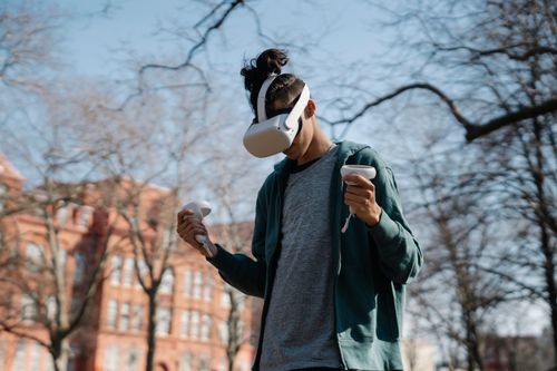 Free Focused anonymous male enjoying game in VR glasses on blurred background of urban building and trees Stock Photo