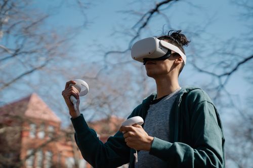 Free Man in virtual reality goggles with controllers playing video game in town on sunny day Stock Photo