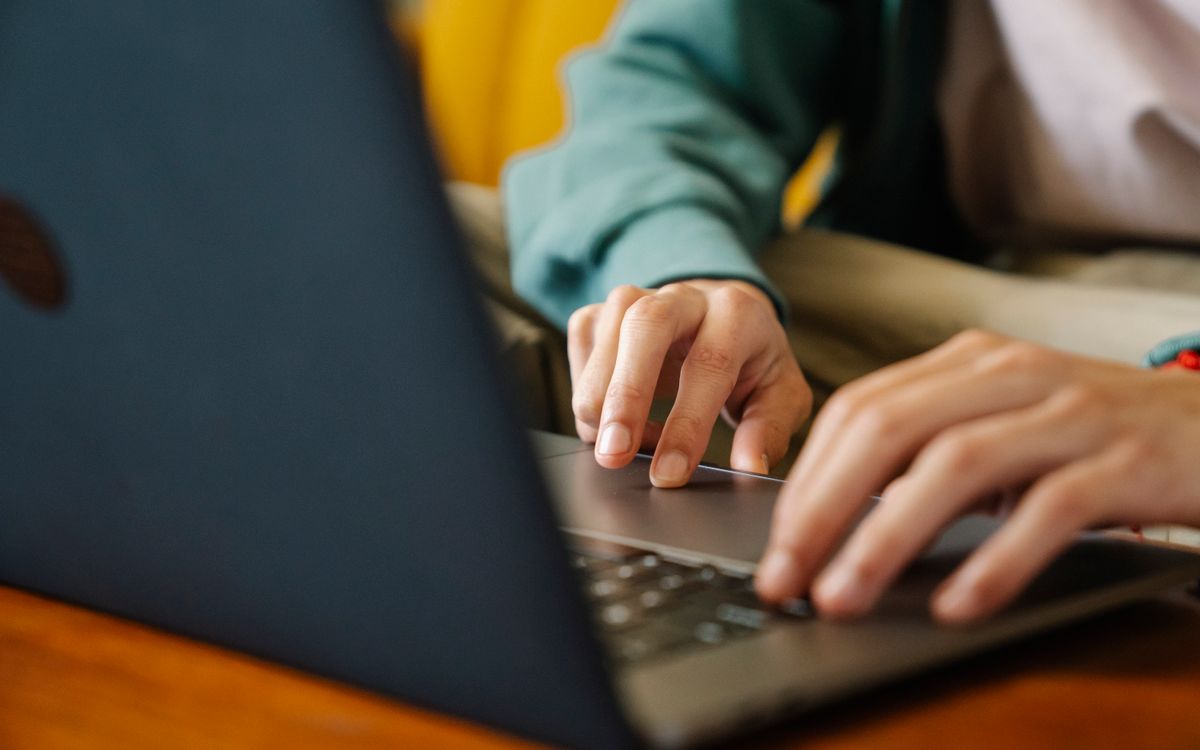 Crop unrecognizable distance employee surfing internet on netbook while working on project at desk in room