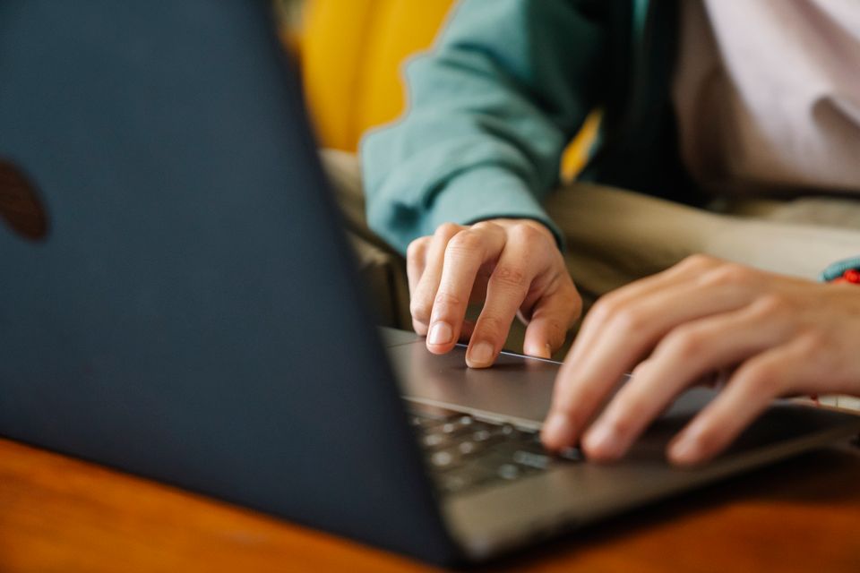 Crop unrecognizable distance employee surfing internet on netbook while working on project at desk in room