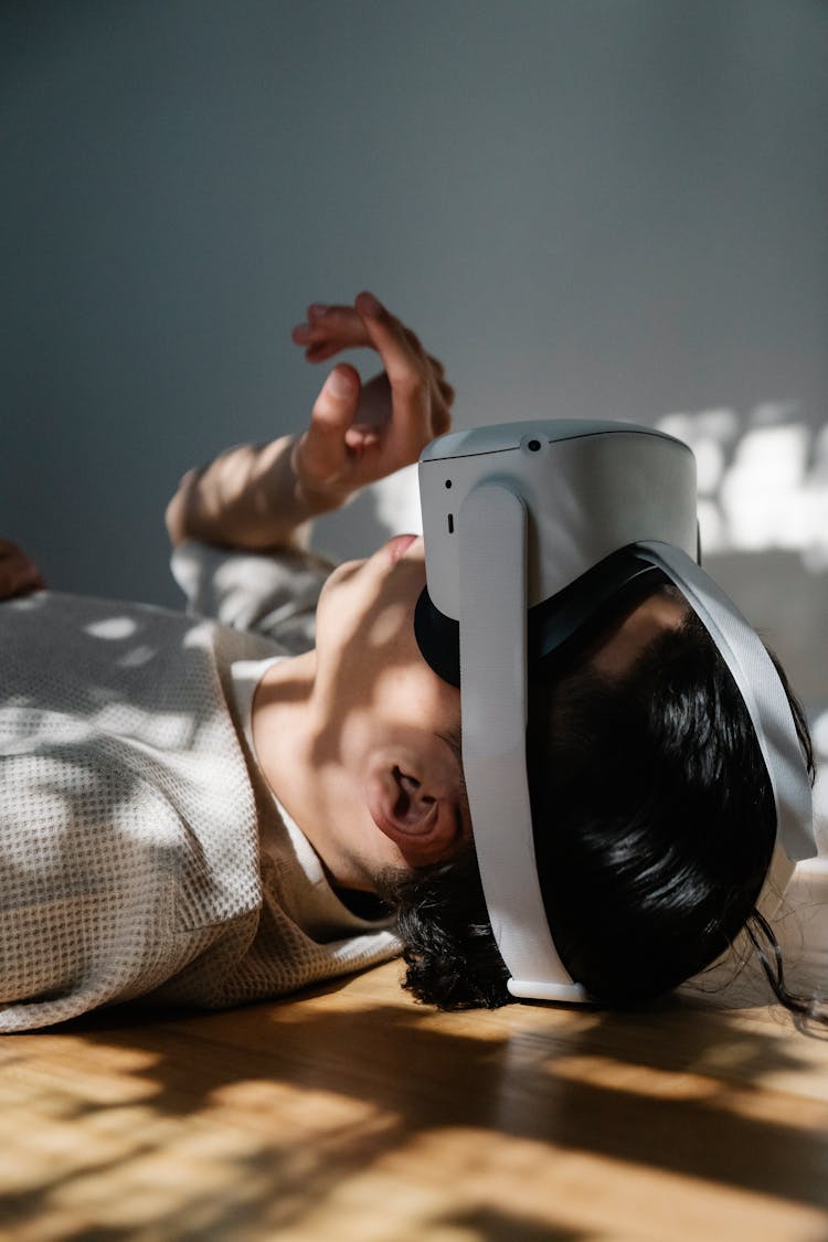 Man Experiencing Virtual Reality In Headset On Floor