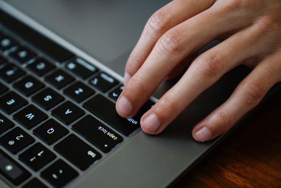 Crop anonymous employee surfing internet on portable computer while working on project at desk in workspace