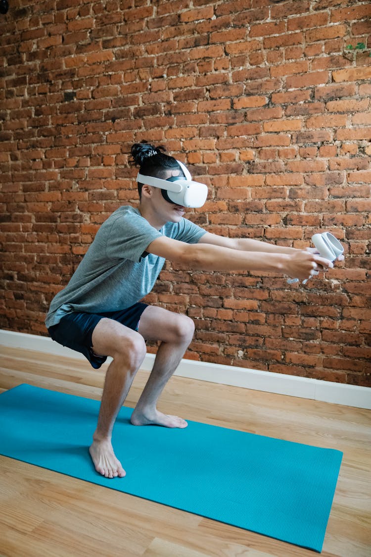 Gamer In VR Goggles Squatting On Yoga Mat In Room