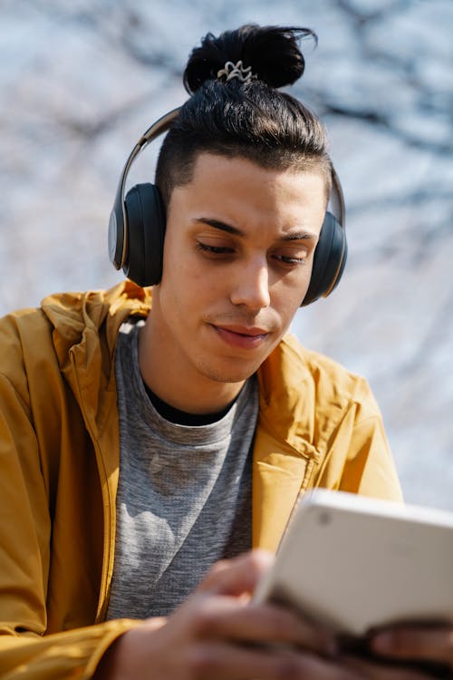 Ethnic man in headphones with smartphone on street