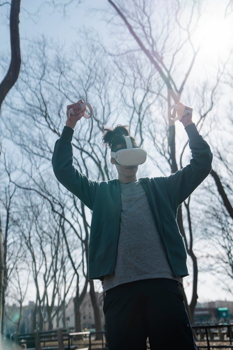 Gamer In VR Goggles Playing Video Game In Park