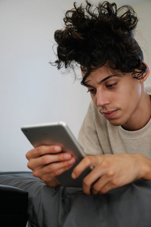 Free A Man Using an Ipad While on the Bed Stock Photo