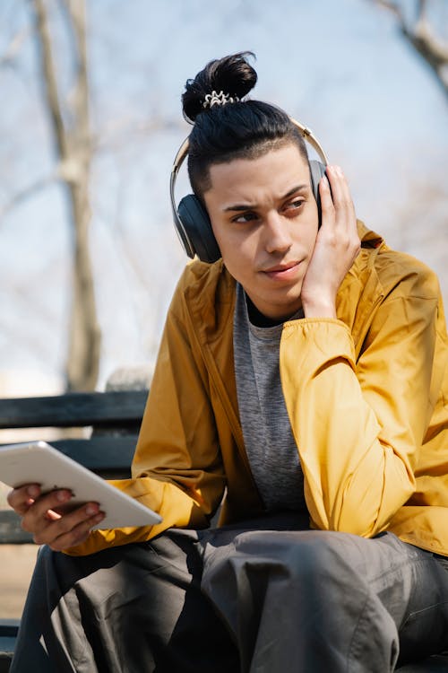 Free Man Wearing a Yellow Jacket Holding a Tablet Stock Photo