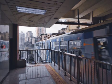 Modern train passing through city station with skyscrapers in background.