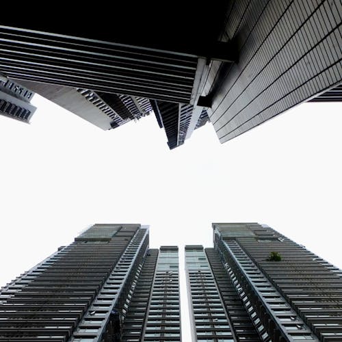 From below of tall contemporary buildings located in city under cloudy sky in daylight