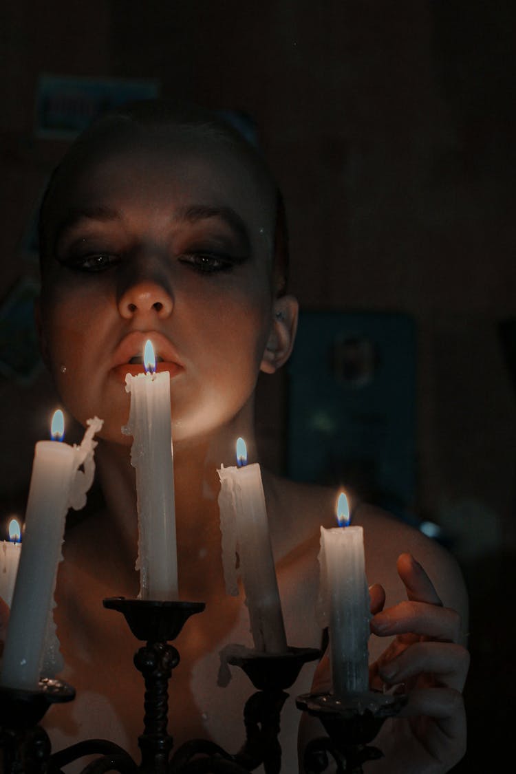 Woman Blowing On Burning Candle At Night